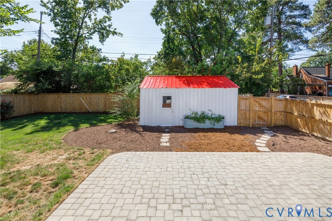 4919 Park Avenue, Near West End, Richmond, VA 23226 Paver patio with a stone pathway, wood privacy fencing, a storage shed with a red metal roof, and a raised garden bed