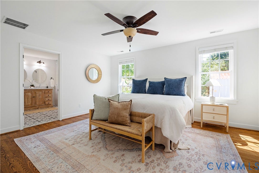 4919 Park Avenue, Near West End, Richmond, VA 23226 Hardwood flooring throughout, ceiling fan with integrated lighting, multiple windows, and a bathroom entry featuring a double vanity with round mirrors and wall-mounted lighting