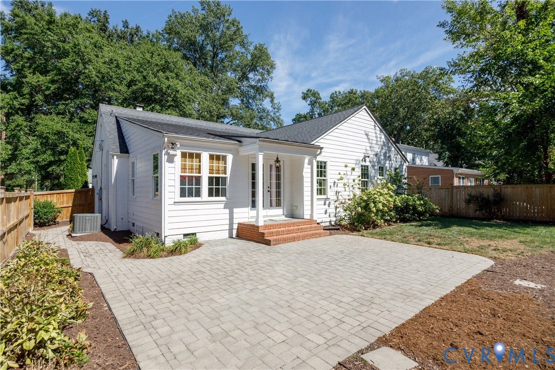 4919 Park Avenue, Near West End, Richmond, VA 23226 White siding exterior with multiple windows, leading to a paver patio with a brick landing