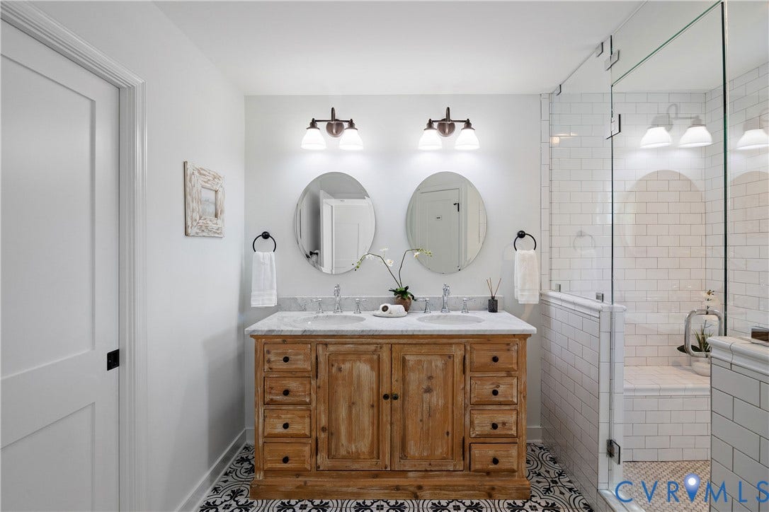 4919 Park Avenue, Near West End, Richmond, VA 23226 Dual vanity with a stone countertop, individual oval mirrors, and a glass-enclosed shower featuring subway tile