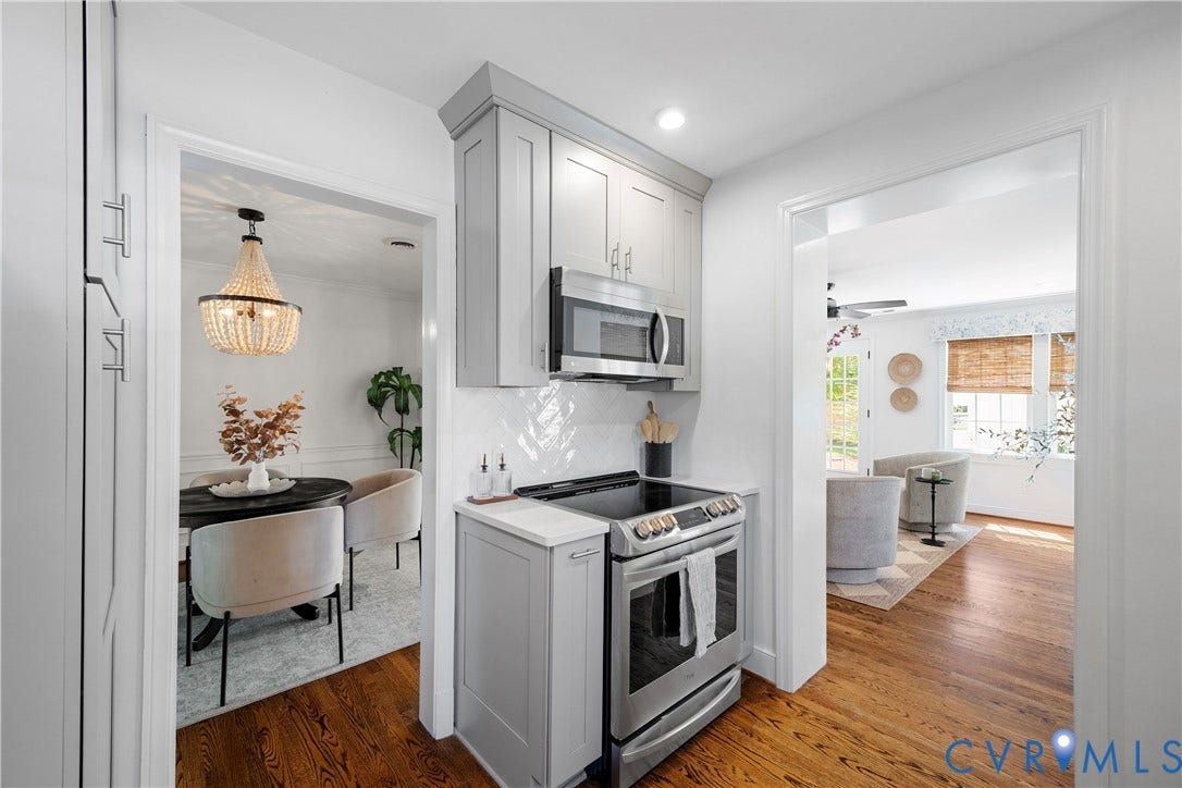 4919 Park Avenue, Near West End, Richmond, VA 23226 Stainless steel range with an overhead microwave, grey upper and lower cabinetry, and a white herringbone tile backsplash