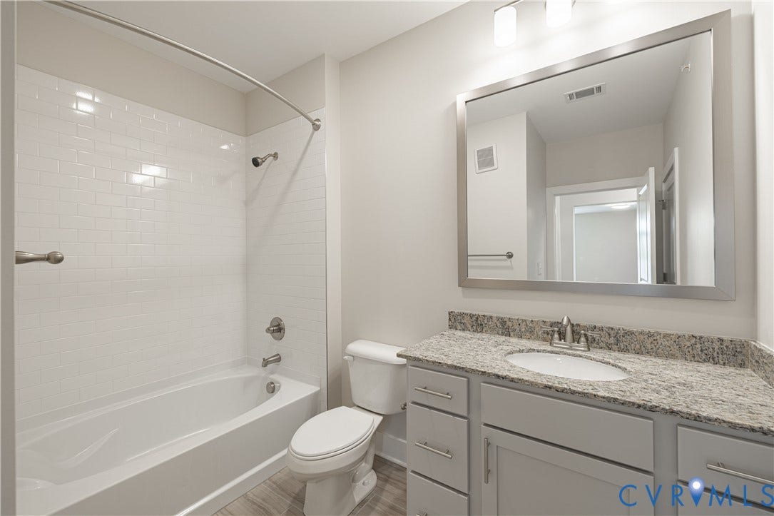 10526 Stony Bluff Drive, #302, Stony Run Condos, Ashland, VA 23005 Bathroom featuring a white subway tile shower surround, a bathtub with brushed nickel fixtures, a single vanity with a stone-finish countertop, and wood-finish flooring
