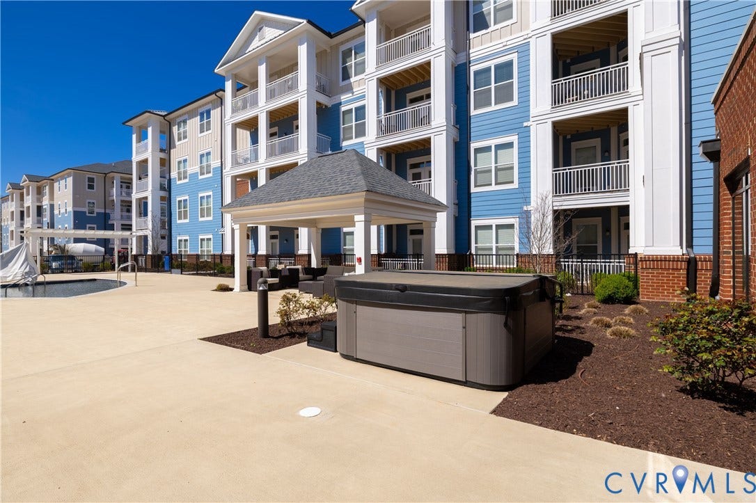10526 Stony Bluff Drive, #302, Stony Run Condos, Ashland, VA 23005 Outdoor hot tub, covered patio area, concrete hardscaping, landscaped planting beds, and multi-story residential buildings