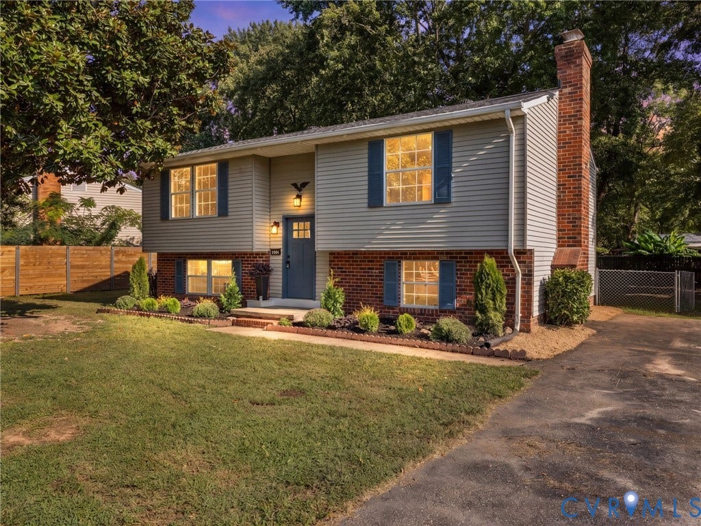 5907 Stella Road, Richmond, VA 23234 Split-level exterior featuring brick and siding, a prominent brick chimney, a driveway, and established landscaping