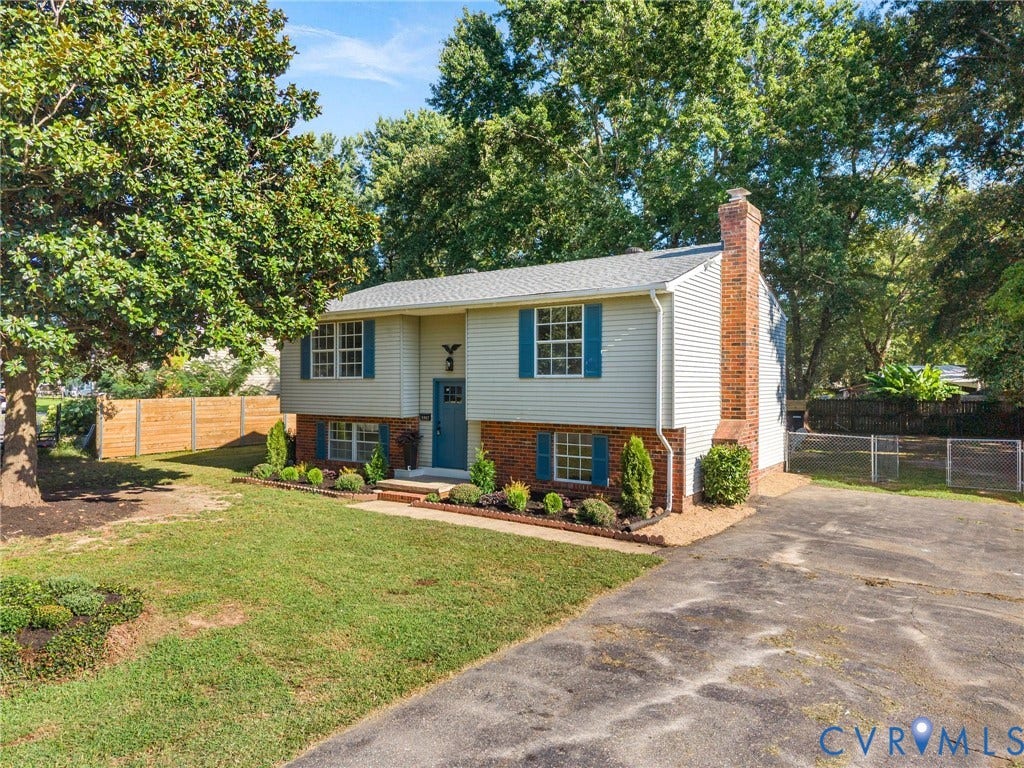 5907 Stella Road, Richmond, VA 23234 Split-level residence featuring brick and siding exterior, a prominent brick chimney, and a landscaped front yard with mature trees