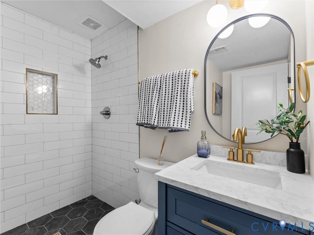 5907 Stella Road, Richmond, VA 23234 Subway tile shower surround with hexagon tile floor, a shower niche, and a rain shower head