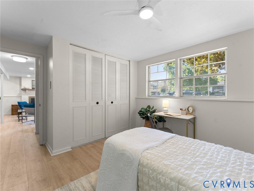 5907 Stella Road, Richmond, VA 23234 Light wood-finish flooring, two large windows, white louvered bifold closet doors, and an overhead ceiling fan with integrated lighting