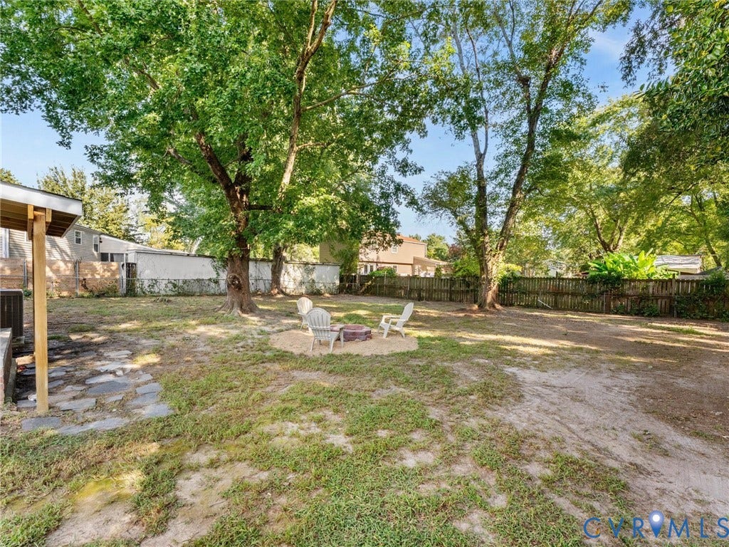 5907 Stella Road, Richmond, VA 23234 Expansive backyard featuring mature trees, a wood privacy fence, and a stone-paved patio area