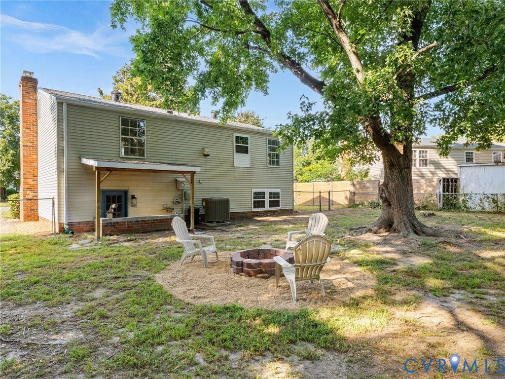 5907 Stella Road, Richmond, VA 23234 Rear exterior with a brick chimney, covered patio, multiple windows, and a mature tree