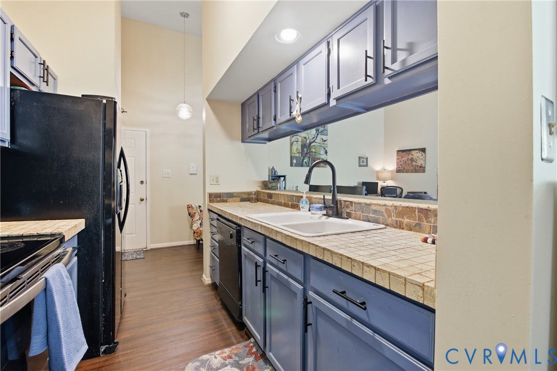 Kitchen featuring LVP flooring, blue cabinetry, a double basin sink with a gooseneck faucet, and tiled countertops with a stone backsplash