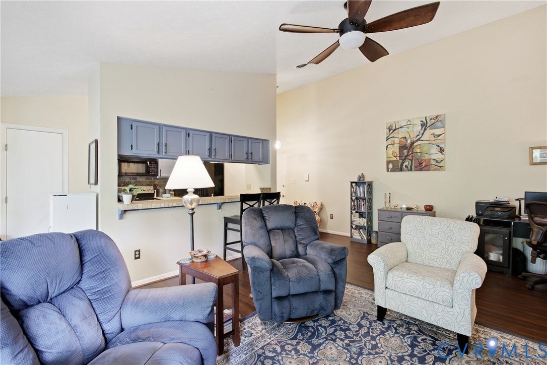 Living area featuring vaulted ceilings, LVP flooring, and a ceiling fan with integrated lighting