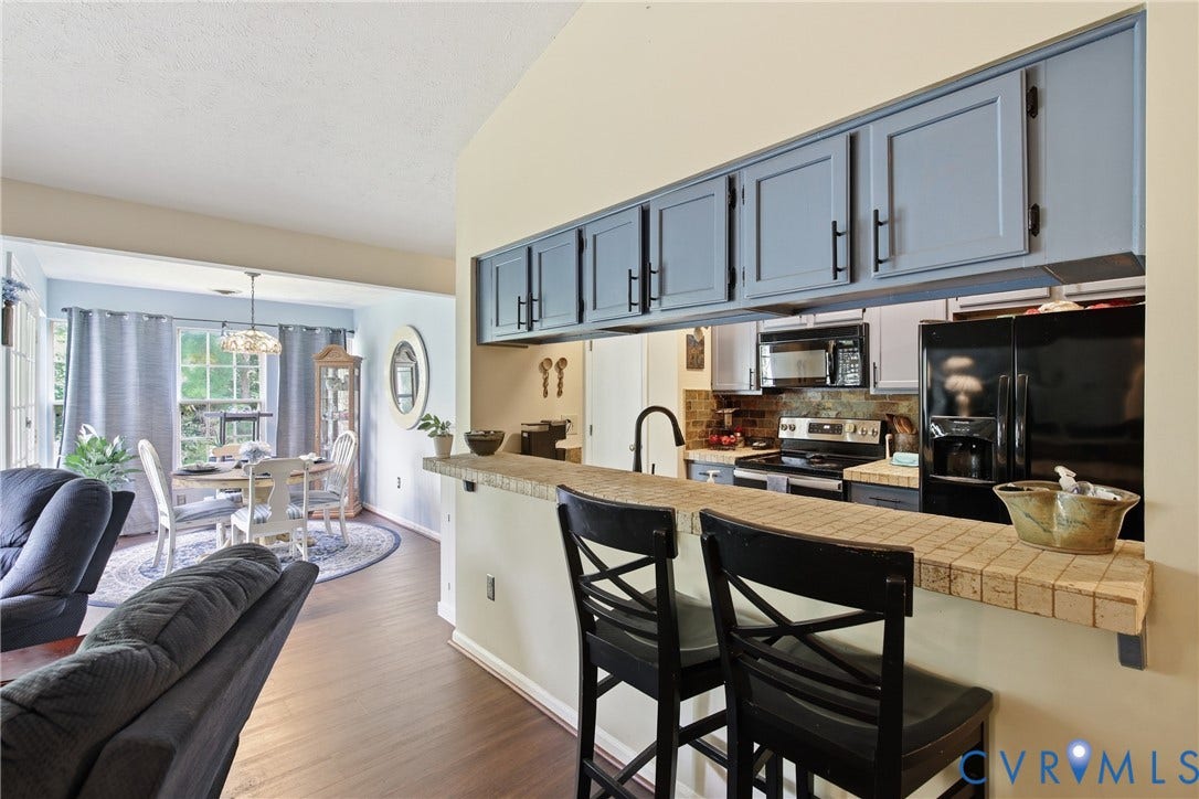 Kitchen pass-through with tile counter seating, LVP flooring, and blue cabinetry