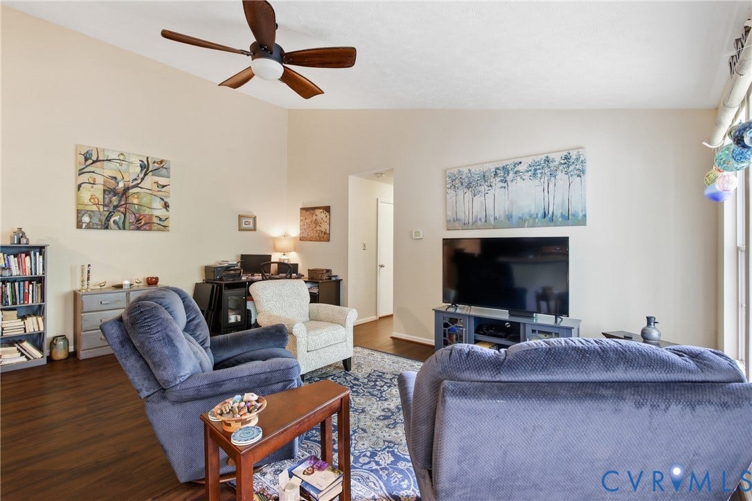 Vaulted ceiling featuring a ceiling fan, LVP flooring, and natural light from large windows