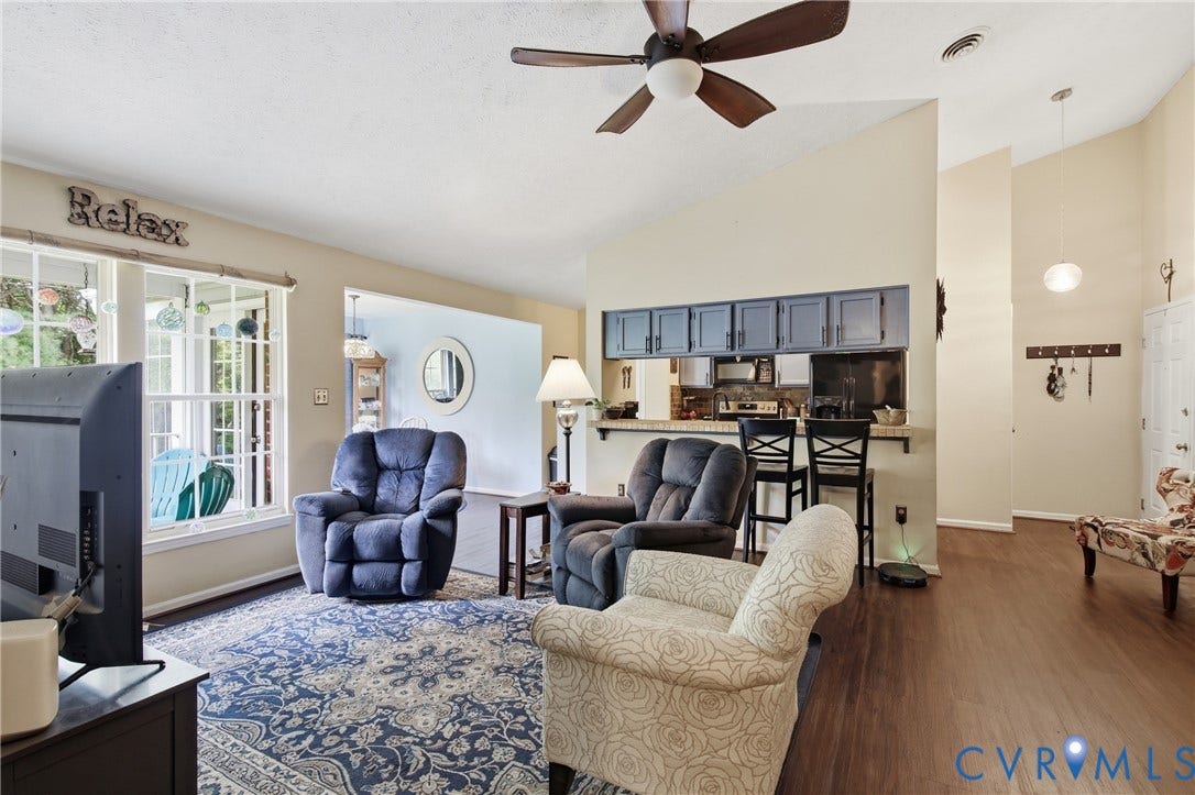 Vaulted ceiling with a ceiling fan, LVP flooring, kitchen pass-through with breakfast bar.