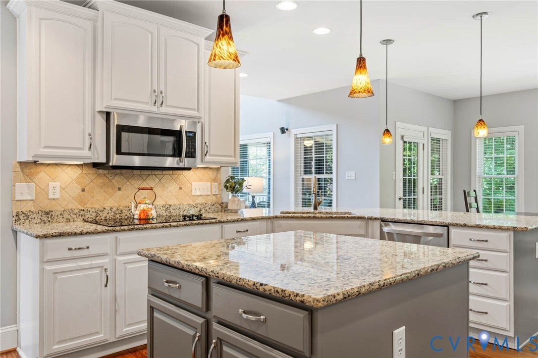 Kitchen featuring granite countertops, white cabinetry, stainless steel appliances, and pendant lighting