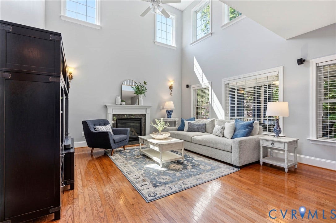 Hardwood flooring, vaulted ceilings with transom windows, and a fireplace with a white mantel