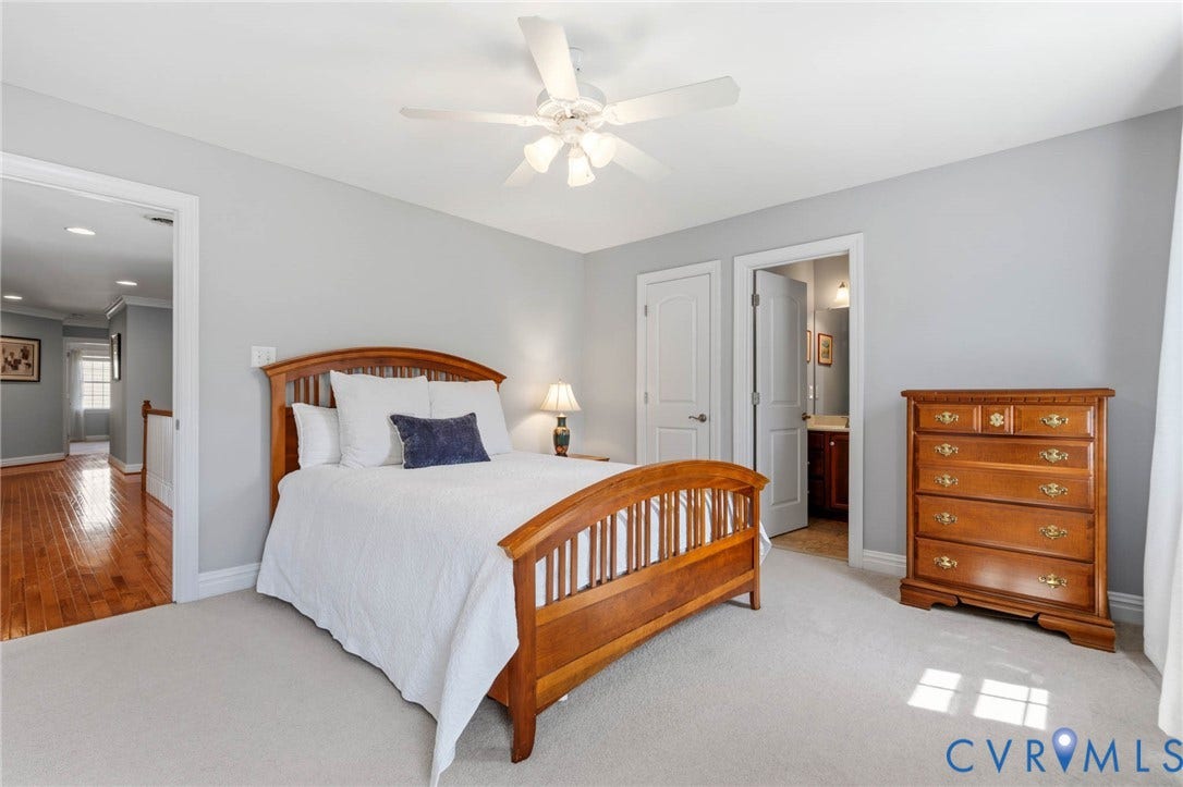 Plush carpeting, ceiling fan, and access to a hallway with wood-finish flooring