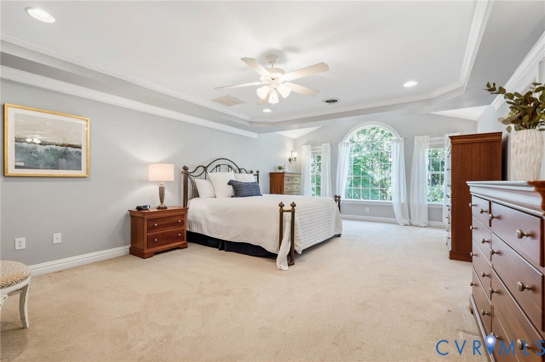 Tray ceiling with crown molding, carpeted flooring, arched window, recessed lighting, and ceiling fan