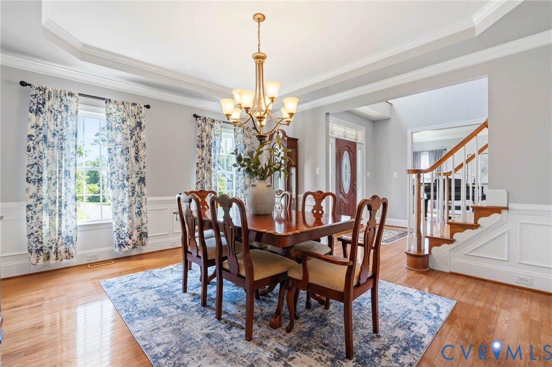 Wood-finish flooring, white wainscoting, tray ceiling, and a chandelier with glass shades