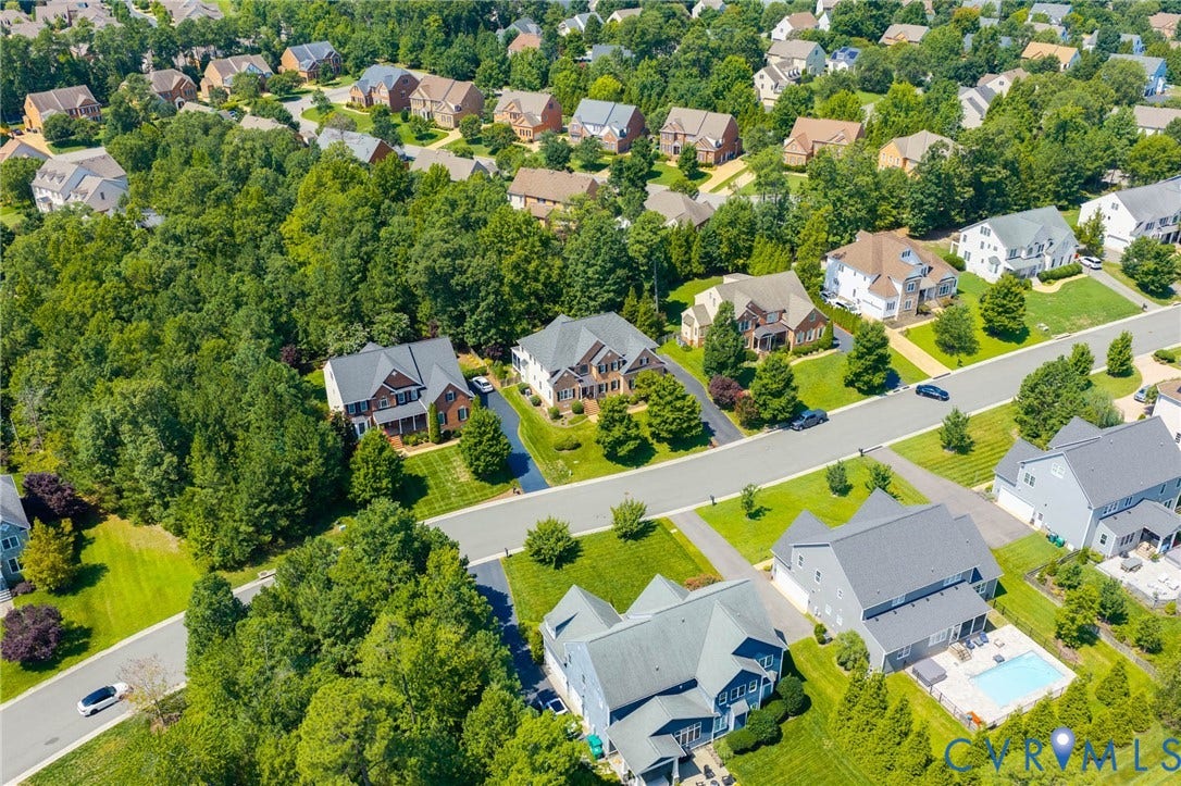 Expansive residential community featuring mature trees, paved streets, and a variety of architectural styles, including a property with a private swimming pool