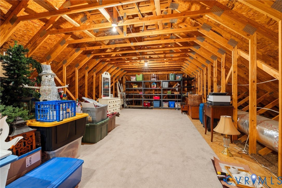 Spacious attic space featuring exposed wood framing, wood paneling, and carpeted flooring