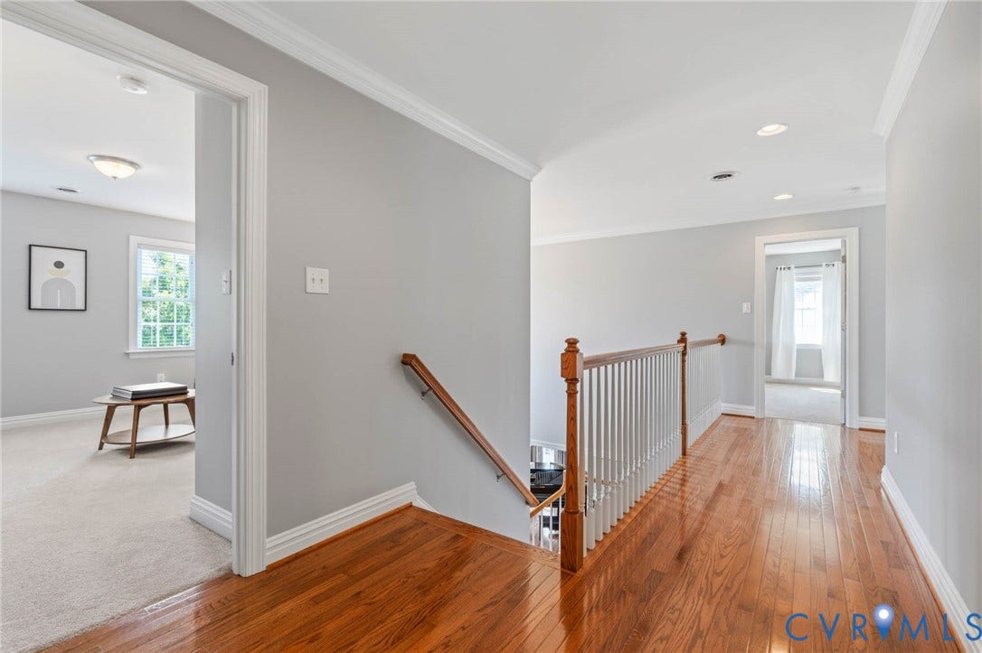 Hardwood flooring in the hallway, white painted balusters with wood railing, recessed lighting, and crown molding