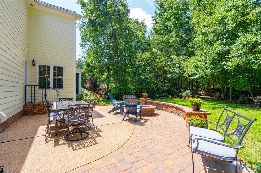 Expansive outdoor patio featuring paver stones, a built-in fire pit, and a stone retaining wall