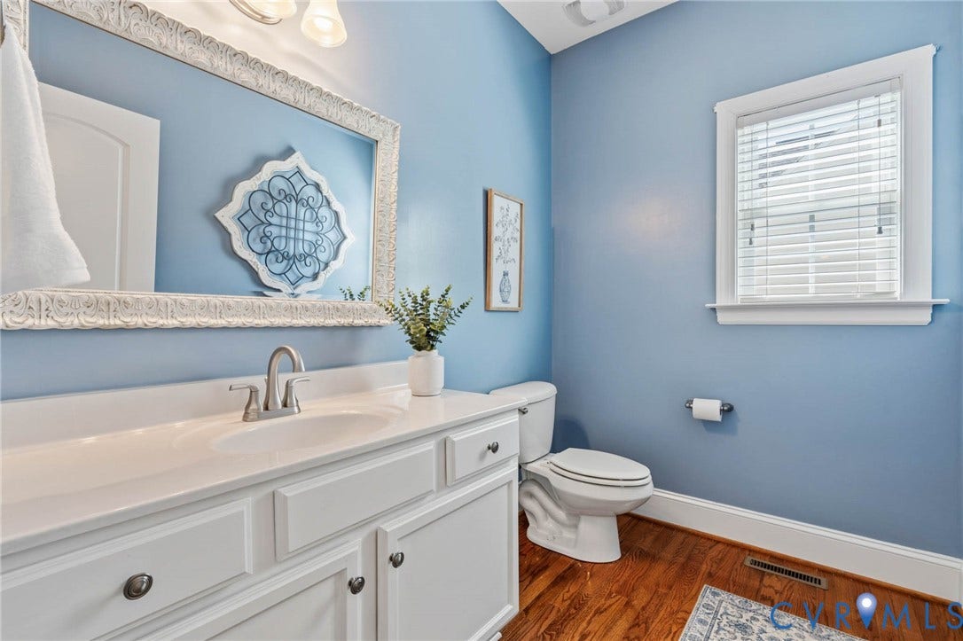 Half Bathroom with wood-finish flooring, white vanity with integrated sink, and a window with blinds