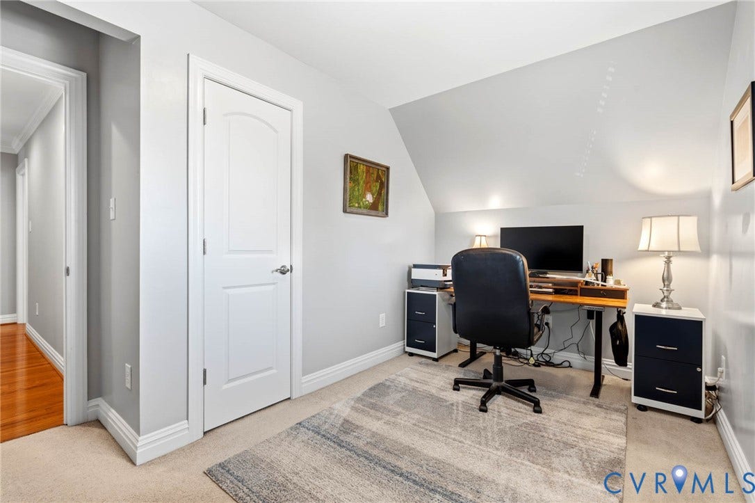 Carpeted flooring with a contrasting area rug, white trim work, and an arched interior door