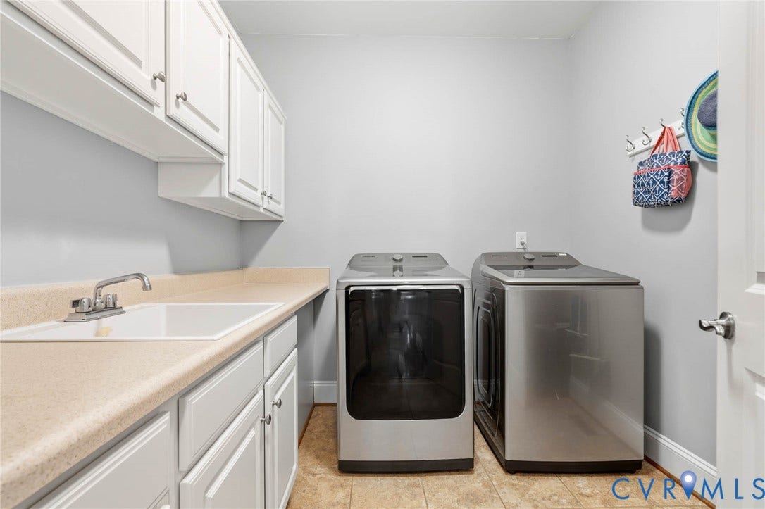 White shaker cabinetry, light-colored countertops, and a white utility sink with a chrome faucet