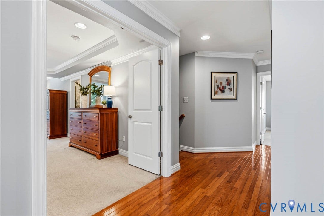 Hardwood flooring, recessed lighting, crown molding, arched doorway, and tray ceiling in an interior space