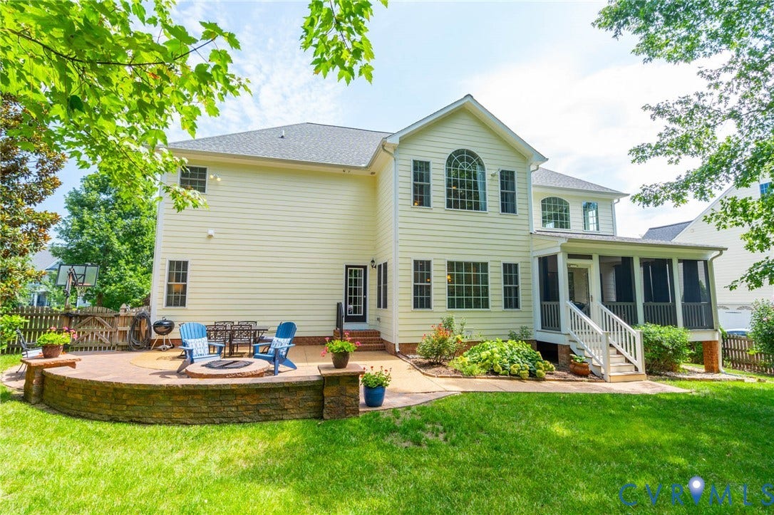Expansive backyard with a manicured lawn, a large paver patio, a built-in fire pit, and a screened porch