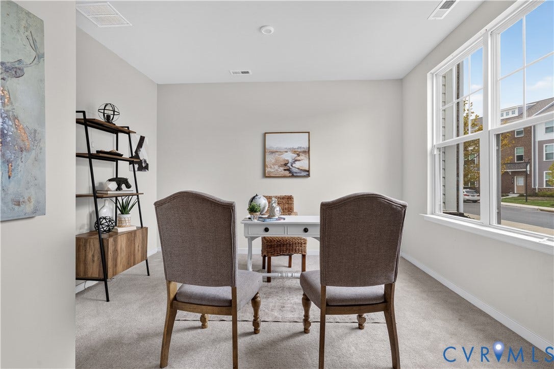 Light-filled interior space with a large window, recessed lighting, and light-toned carpeting