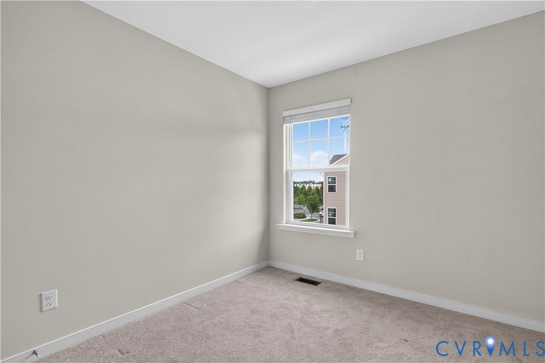 Neutral wall finish, carpeted flooring, and a window with white trim