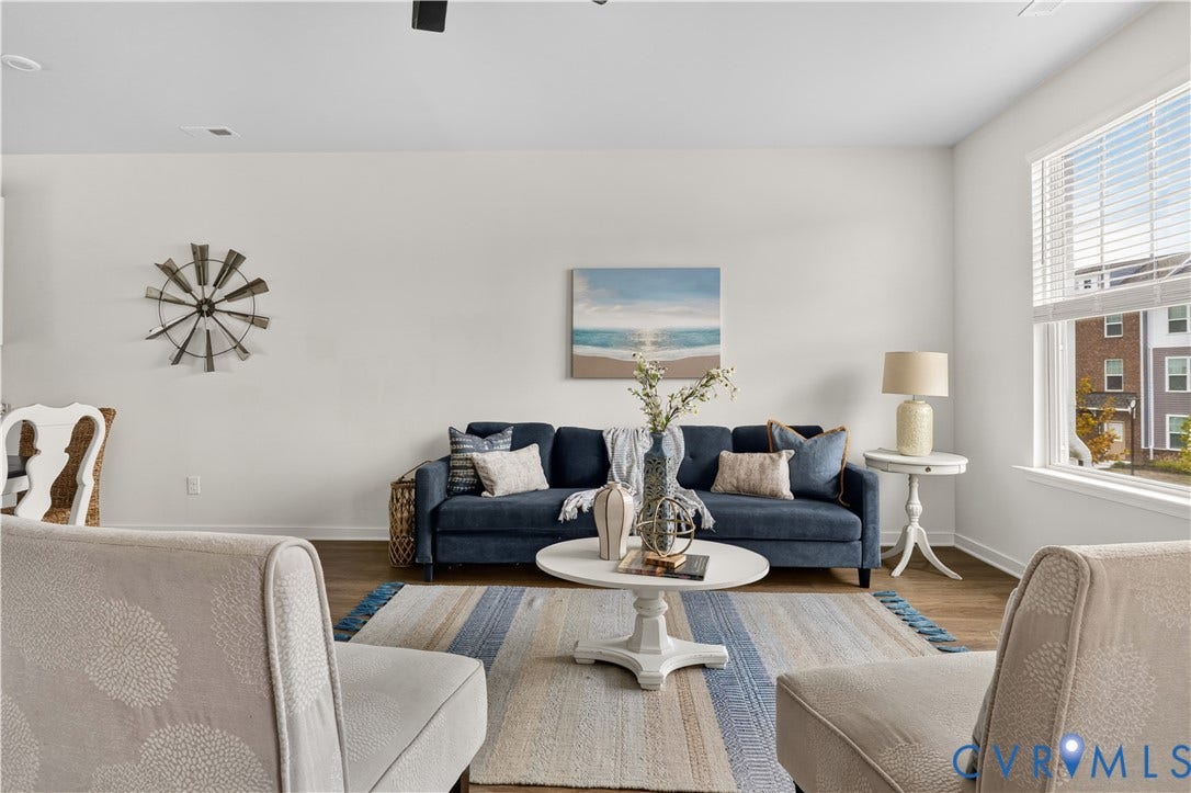 Spacious living area featuring high ceilings, wood-finish flooring, recessed lighting, and a large window with blinds