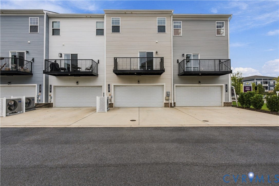 Townhome residences featuring multi-level construction, individual garage access, private balconies with black railings, and horizontal siding
