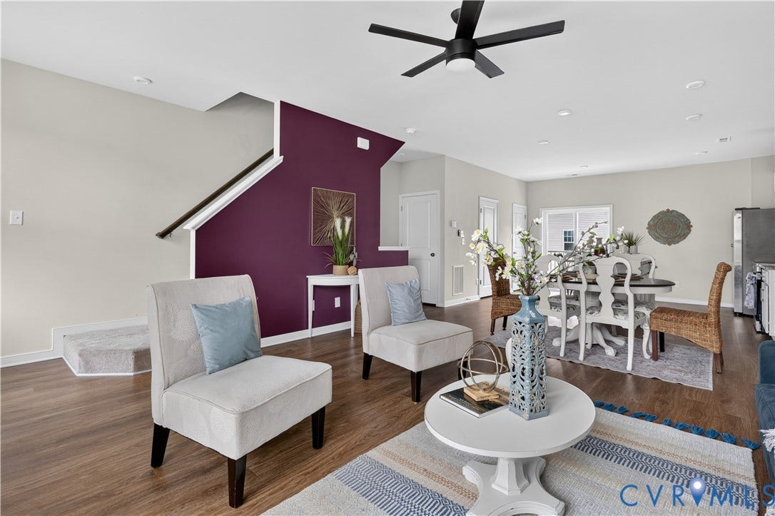 Open-concept living area with wood-finish flooring, a contemporary ceiling fan, recessed lighting, and a staircase with a dark wood handrail