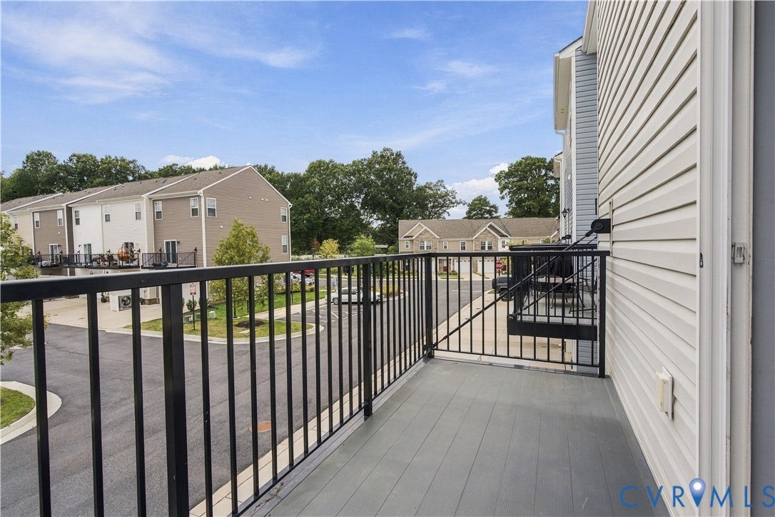 Balcony with black metal railings and composite decking, featuring light-colored horizontal siding