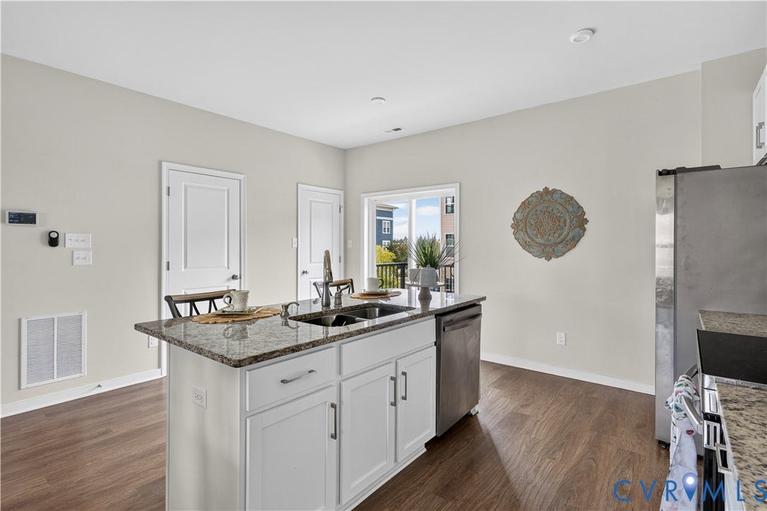 Kitchen featuring a central island with a dual-basin sink, light-toned cabinetry, and a granite-style countertop