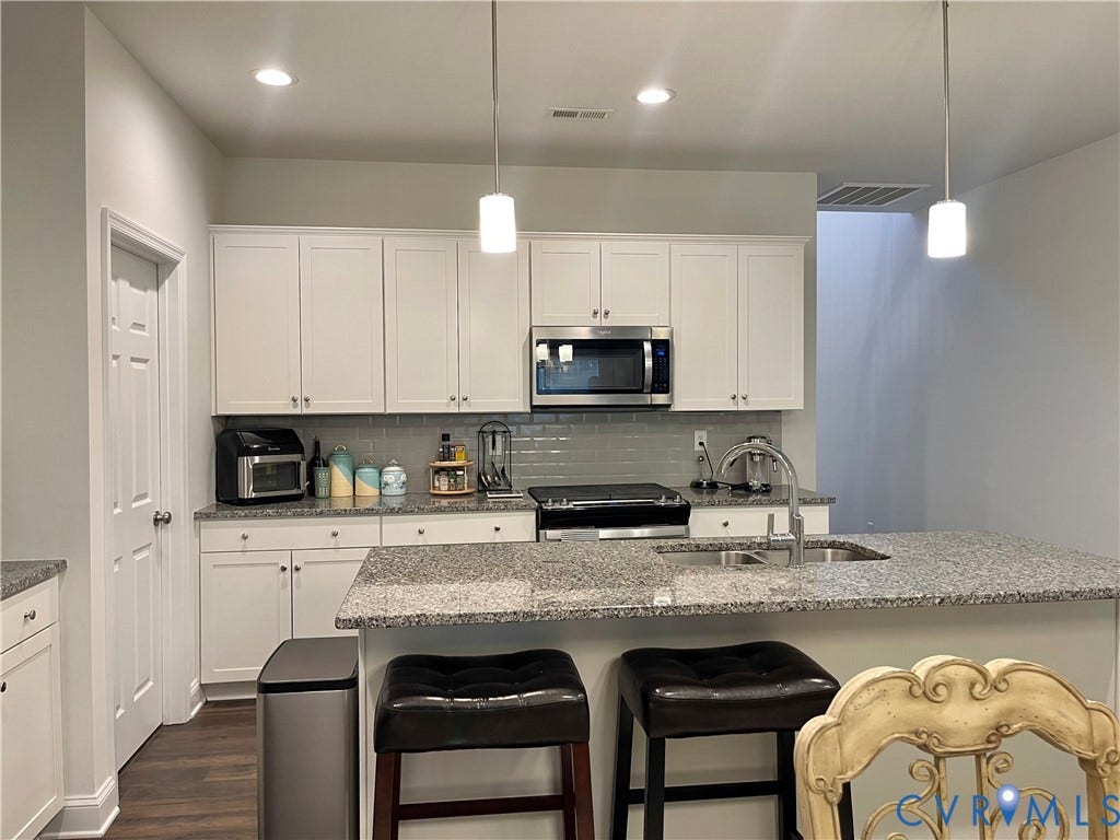 6905 Leire Lane, Chesterfield, VA 23832 Spacious kitchen featuring white cabinetry, gray subway tile backsplash, stainless steel appliances, granite countertops, and an island with a stainless steel sink