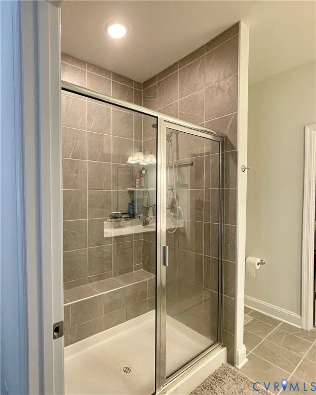 6905 Leire Lane, Chesterfield, VA 23832 Shower enclosure featuring clear glass sliding doors, full-height tile surround, an integrated bench, and a recessed niche