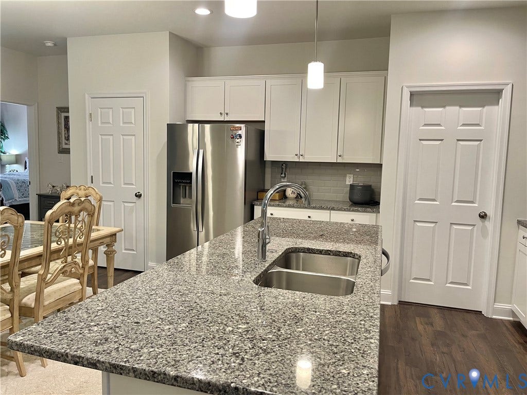 6905 Leire Lane, Chesterfield, VA 23832 Kitchen featuring an island with a double basin stainless steel sink, light-toned countertop, white cabinetry, and stainless steel refrigerator