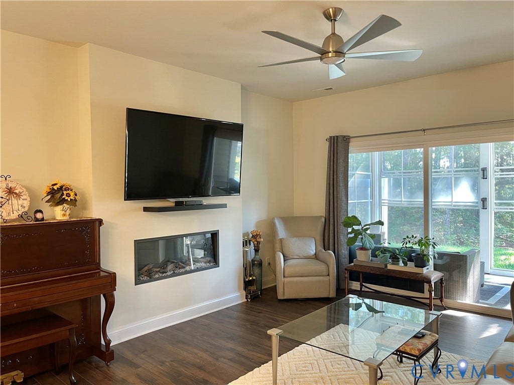6905 Leire Lane, Chesterfield, VA 23832 Wood-finish flooring, ceiling fan with brushed nickel finish, mounted television, linear electric fireplace, and sliding glass door leading to the exterior