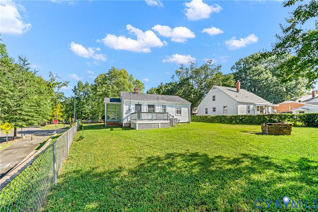 Expansive fenced yard featuring a wood deck, screened porch, and a built-in fire pit