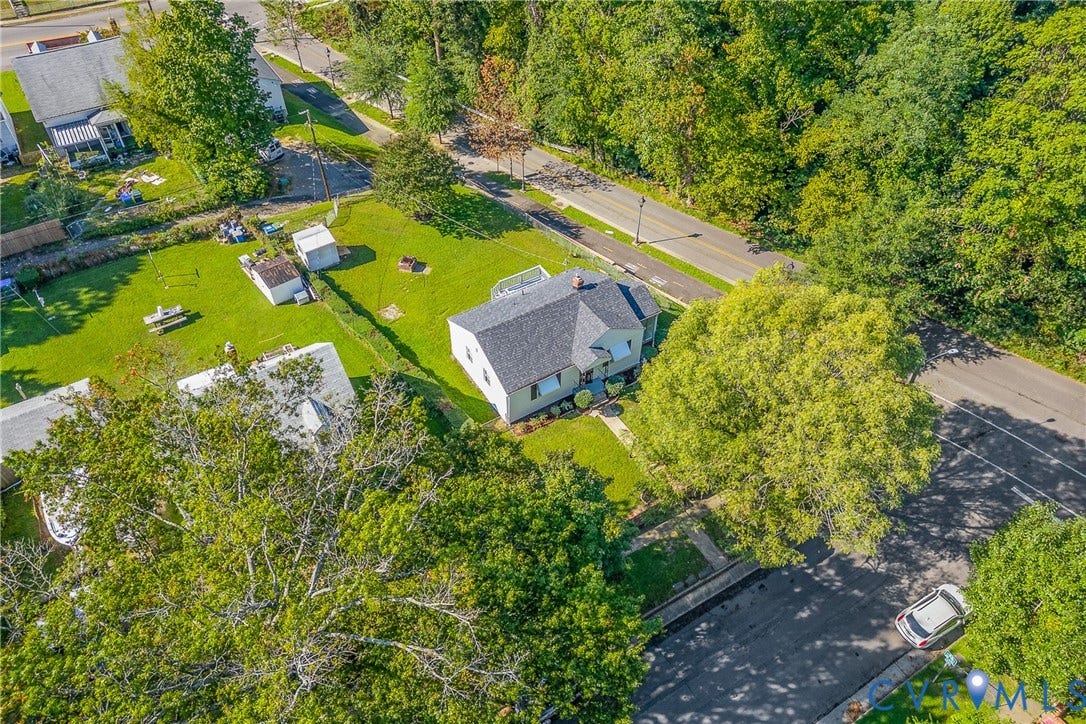 Expansive grassy lot featuring mature trees and a detached structure