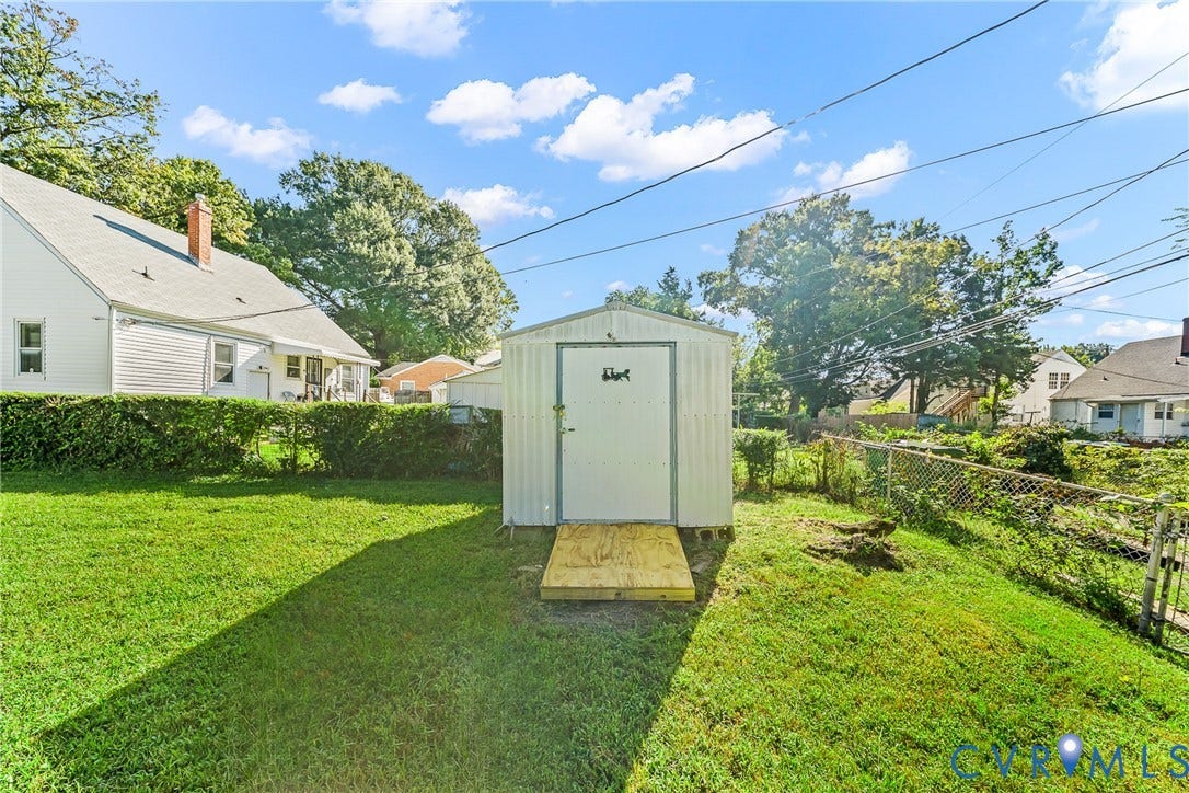 Expansive yard featuring a metal storage shed, wood ramp entry, and chain-link fencing