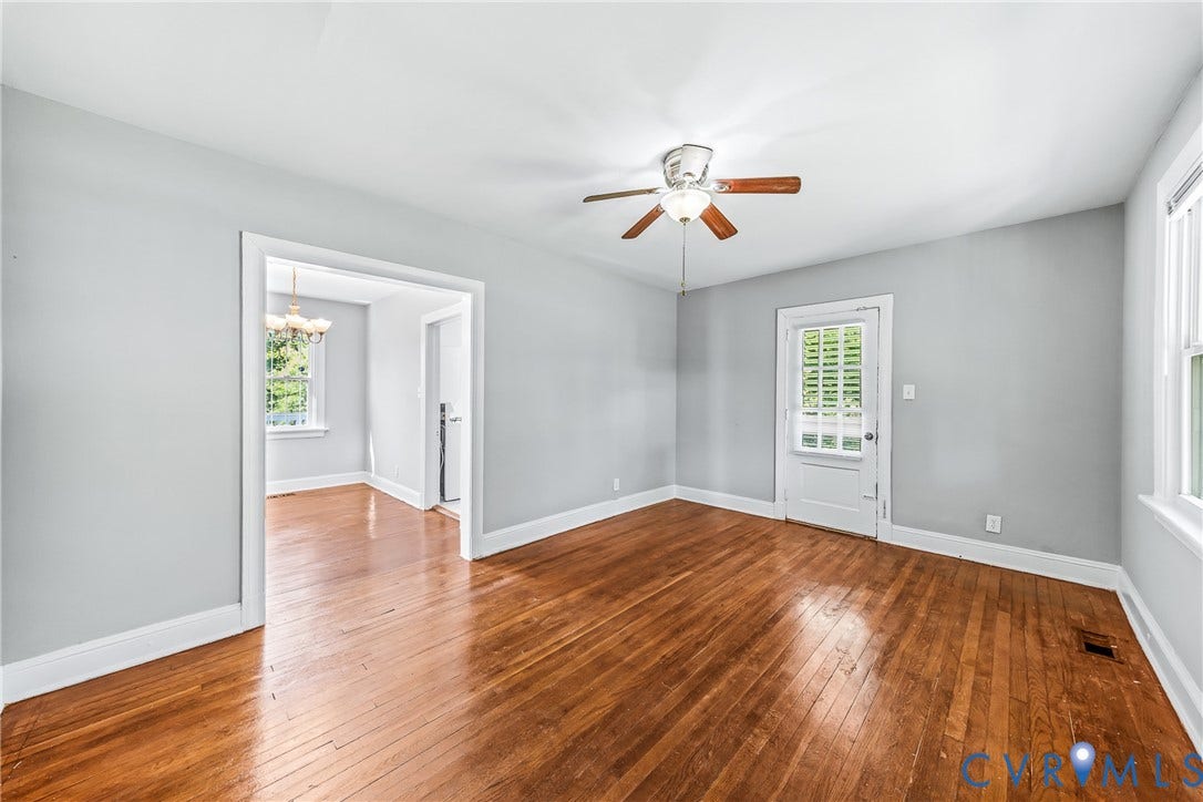 Hardwood flooring throughout, ceiling fan, white trim, and a paneled door with glass inserts