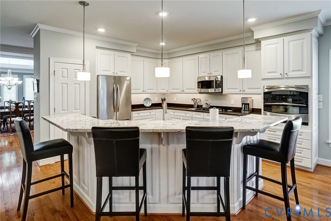 4938 Grey Oaks Villas Drive, Glen Allen, VA 23059 Kitchen featuring white cabinetry, stainless steel appliances, a multi-level island with seating, and wood-finish flooring