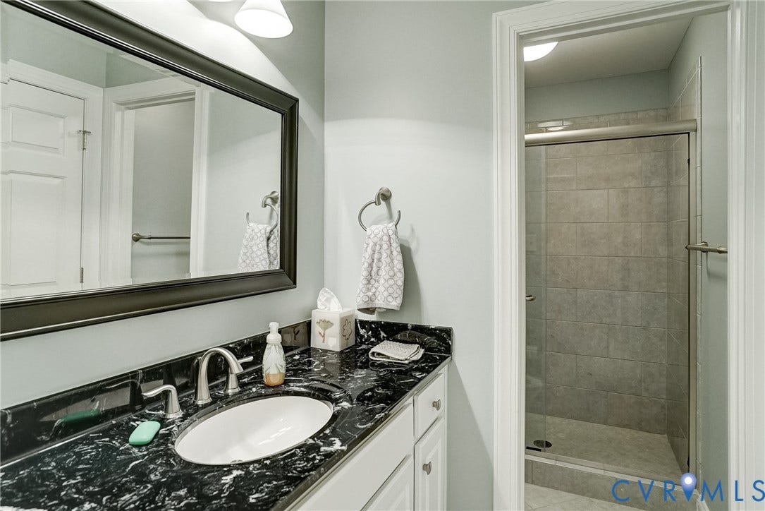 4938 Grey Oaks Villas Drive, Glen Allen, VA 23059 Vanity with a black stone countertop, undermount sink, and brushed nickel faucet