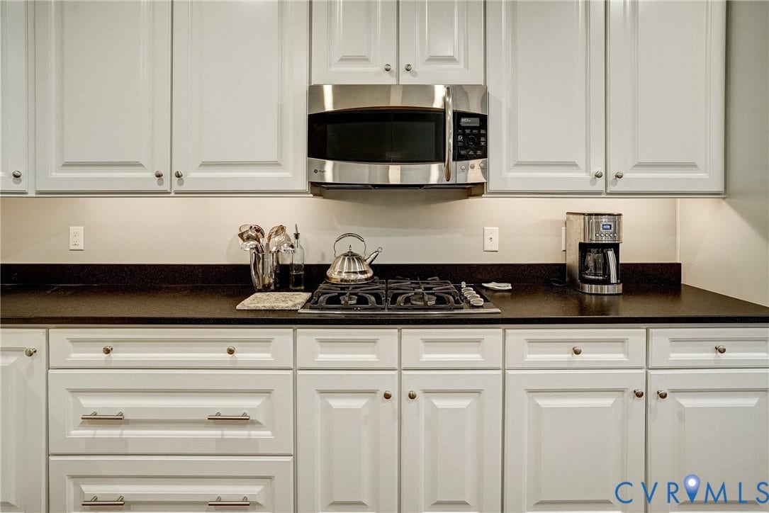 4938 Grey Oaks Villas Drive, Glen Allen, VA 23059 White cabinetry with panel doors, dark countertops, a built-in stainless steel microwave, and an integrated gas cooktop